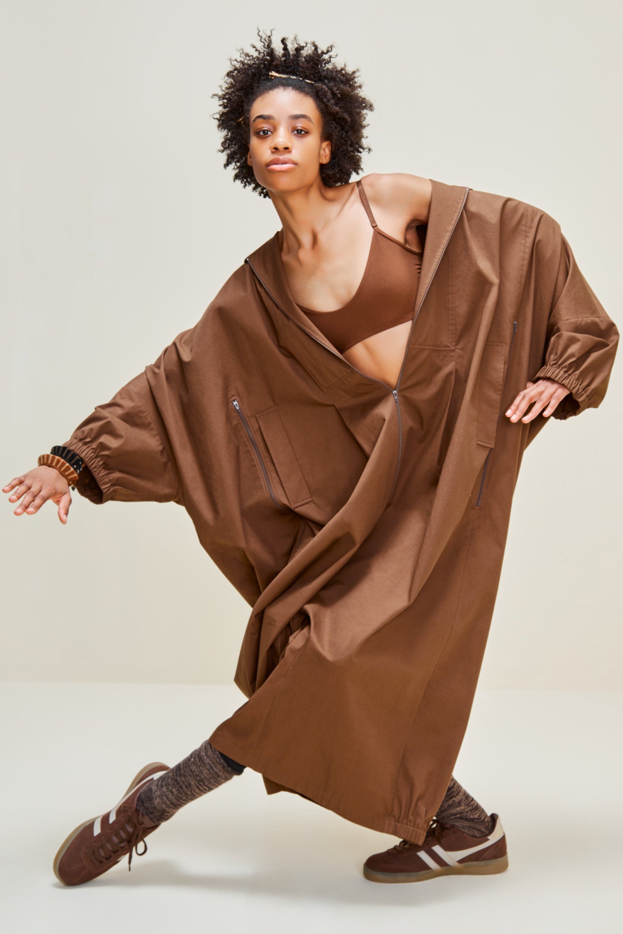 Person wearing a brown dress with a sheer overlay on a white background